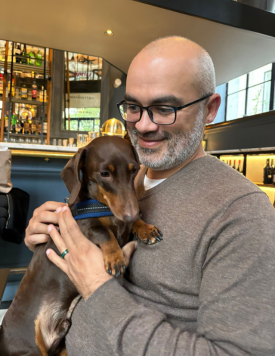 A man hugging a small brown dog in a café